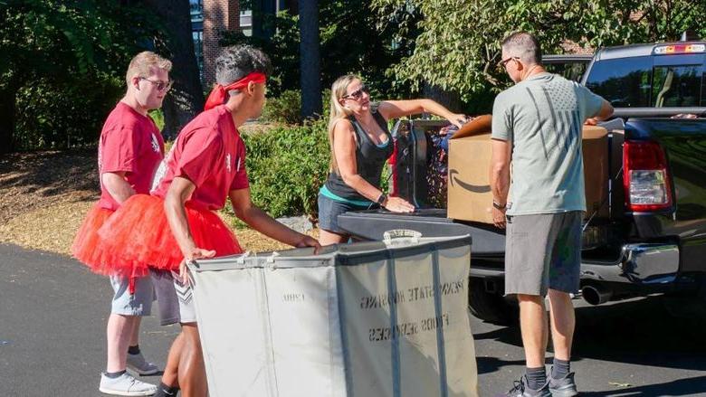 两个学生帮助一家人把箱子从卡车里搬出来.